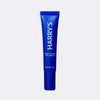 Blue tube of Harry's Brightening Eye Cream on a light gray background
